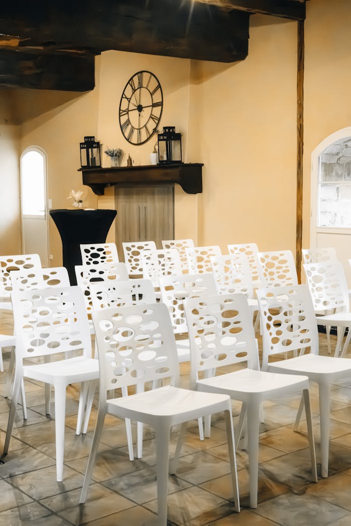 Image of a stylish indoor venue with decorative white chairs arranged for an event.