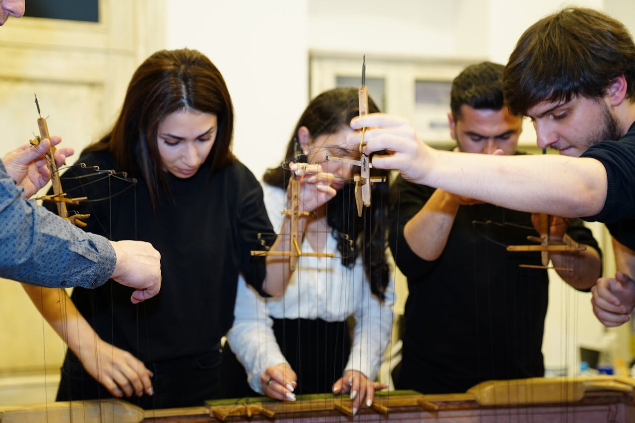 A group of young adults engaging in a puppet crafting workshop, focusing intently on their projects.